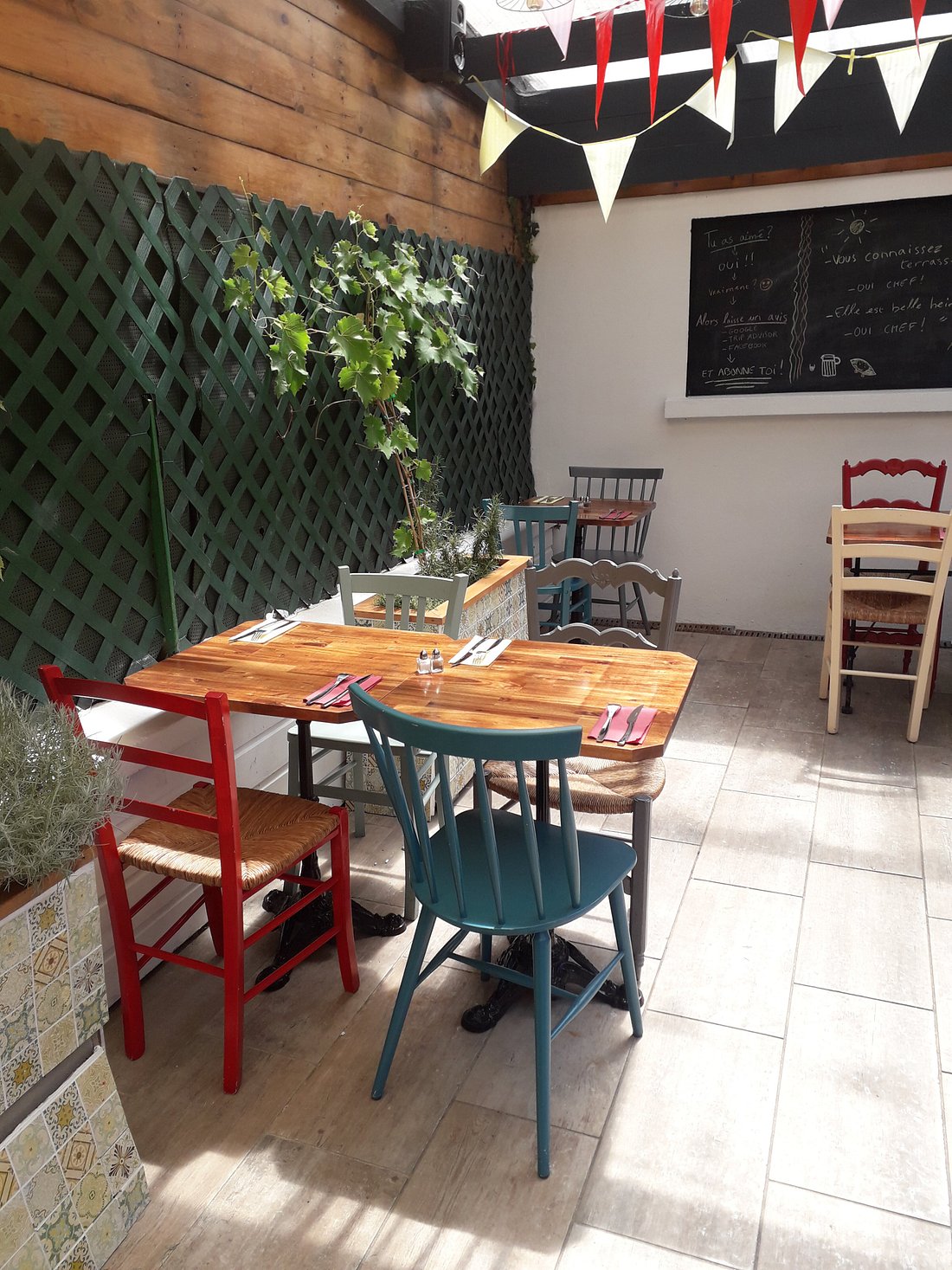 Le patio intime — tables en bois et chaises multicolores